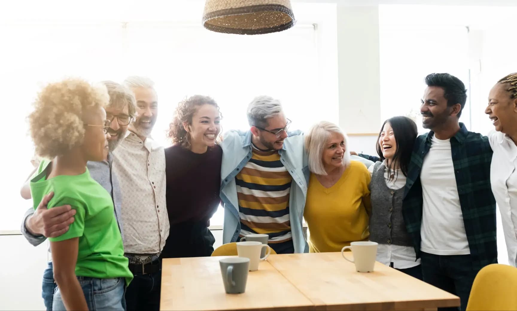 Diverse grupp av bostadsrättsföreningsmedlemmar som umgås och skrattar tillsammans i ett gemensamt kök, förstärker grannskapsgemenskapen